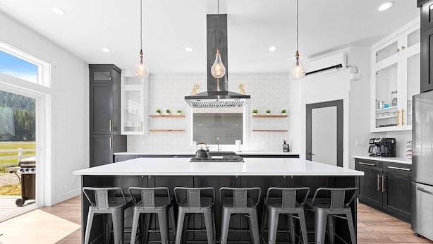 Een moderne keuken met een groot eiland, barkrukken en uitzicht op de omgeving.