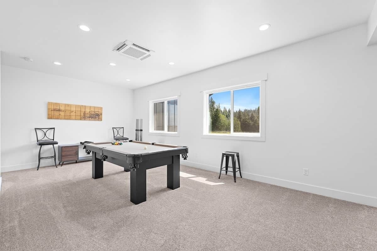 Una habitación amplia con mesa de billar, una silla y ventana con vista a árboles.