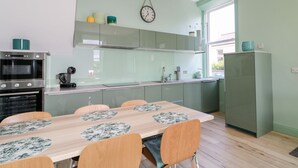 Una cocina moderna con comedor, que incluye una mesa de madera con sillas, horno empotrado y refrigerador.
