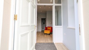 Un pasillo con una puerta blanca, una silla roja y una alfombra gris.