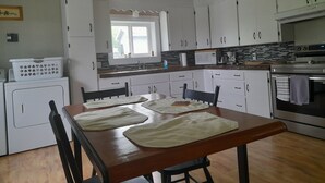 Eine Küche mit weißen Schränken, einem Holzespeisebereich mit Stühlen, einer Mikrowelle und einem Backofen.