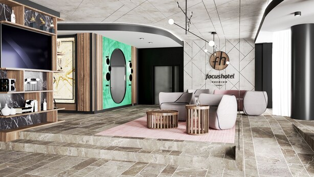 Un rebedor modern amb un taulell de recepció de marbre, una zona de seients amb sofàs i una taula de cafè, i un cartell fixat a la paret per 'focushotel'.