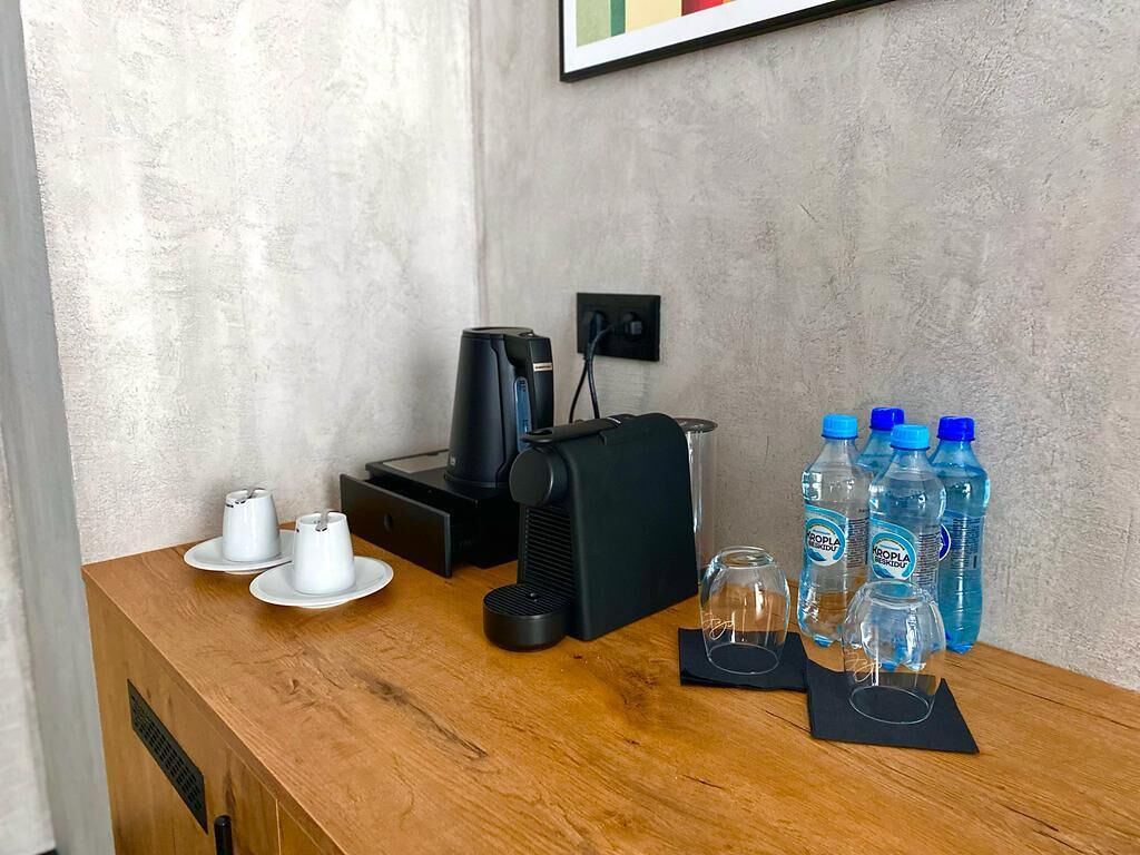 Una mesa de madera con una cafetera, dos tazas y tres botellas de agua.