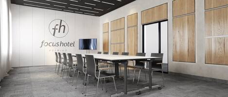A conference room with a whiteboard, a television, and a logo for 'focushotel'.