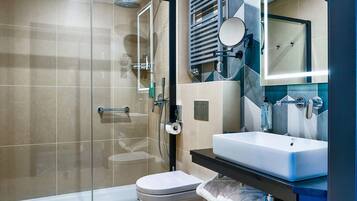 Een moderne badkamer met een douchecabine van glas, een toilet, een wastafel en een spiegel.