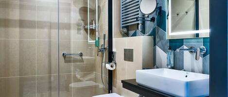 Un baño moderno con cabina de ducha de vidrio, inodoro, lavabo y espejo.