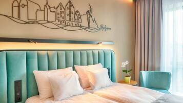 Ein Hotelzimmer mit einem großen Bett, einem Kopfteil mit Stadtbild-Fresko, einer Zimmerpflanze und einem Fenster mit Vorhängen.