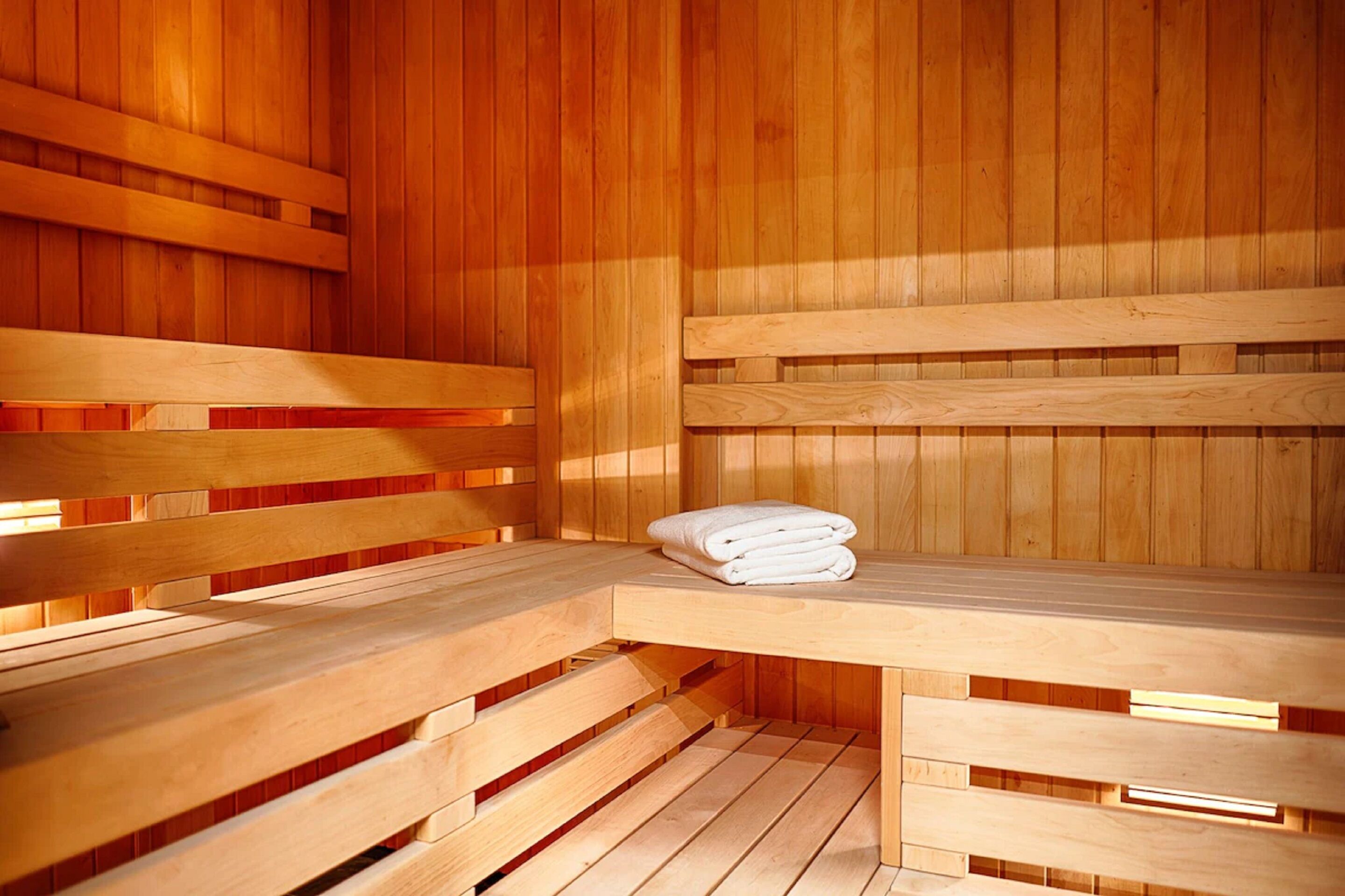 A sauna with wooden benches and a bench with towels.