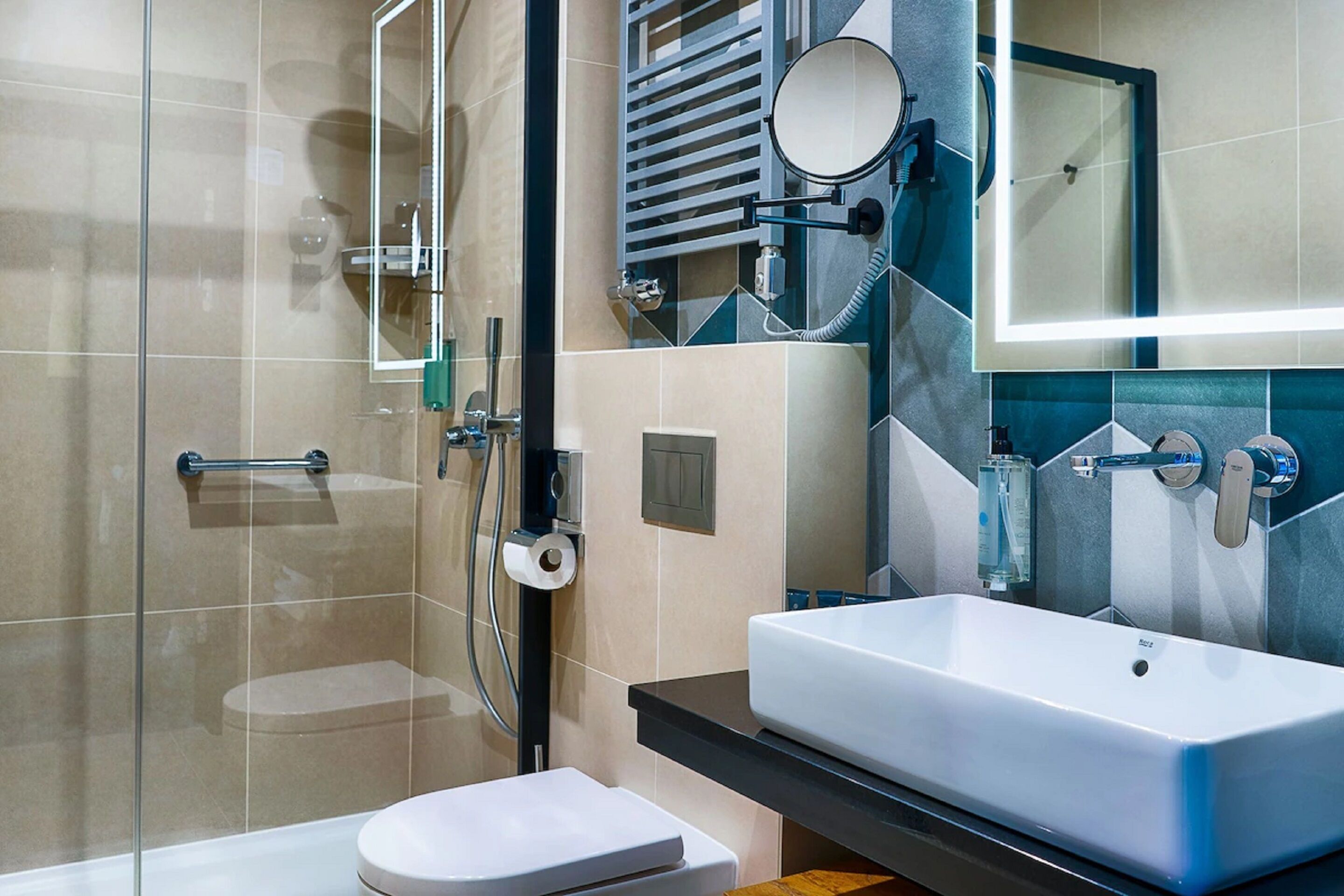 Un baño moderno con cabina de ducha de vidrio, inodoro blanco, lavabo grande con espejo y toallero.
