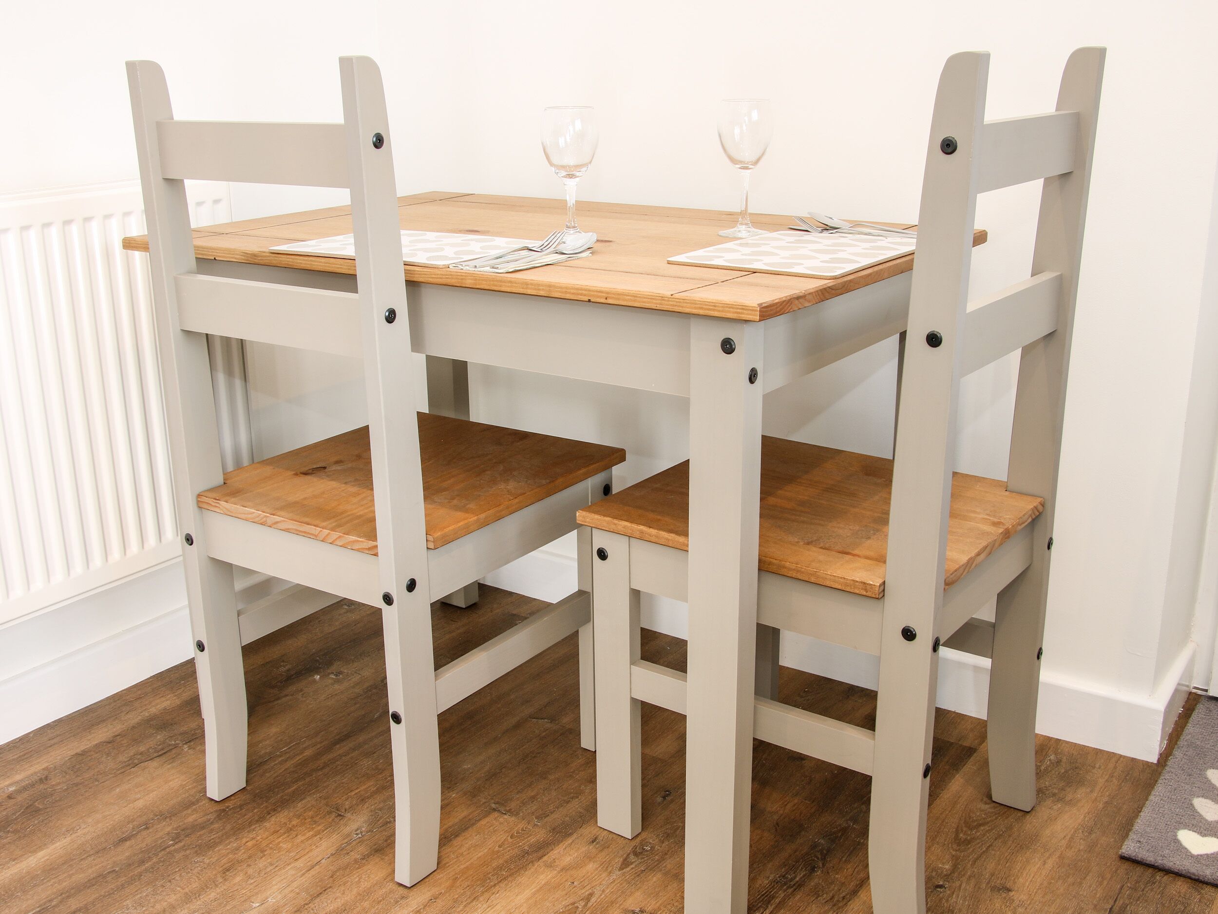 A dining table with four chairs, each with a wooden seat and backrest, and a white tablecloth.