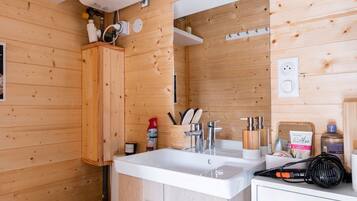 Een compacte, moderne badkamer met een wit toilet, houten kastjes, een wastafel met spiegel en een douchehoek.