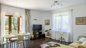 A well-lit room with a dining table set for two, a sofa, a television, and a small table with a plant. - Istria Rosa in Pula - Istrien / Istria Rosa in Pula - Appartement für 4-5 Personen (Pula)
