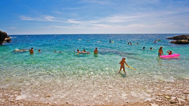 A beach with clear turquoise water, people swimming and playing, and rocky shorelines. - Istria Rosa in Pula - Istrien / Istria Rosa in Pula - Appartement für 4-5 Personen (Pula)