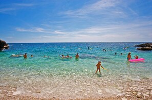 A beach with clear turquoise water, people swimming and playing, and rocky shorelines. - Istria Rosa in Pula - Istrien / Istria Rosa in Pula - Appartement für 4-5 Personen (Pula)