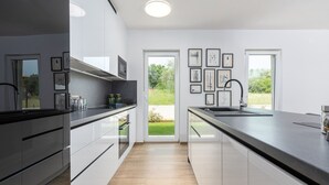 A modern kitchen with a large window, a sink, and a countertop. - Charming Villa Audrey with an outdoor pool (Umag)