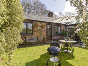 A patio with a grill, a bench, and a table with chairs. - Little Barton (Taunton)