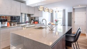 Una cocina moderna con una isla central, electrodomésticos de acero inoxidable e iluminación colgante.
