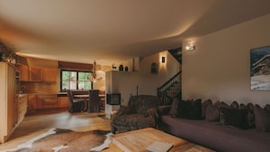 A spacious living area with a wooden floor, a sofa, a coffee table, and a fireplace.
