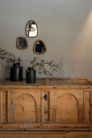 A wooden dresser with three black vases and a clear decanter.