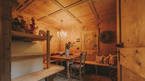 Un interior de madera con una mesa de comedor, bancos y una araña.