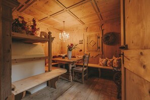 Un interior de madera con una mesa de comedor, bancos y una araña.