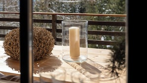 A wooden table with a glass candle holder and a candle, a decorative sphere, and a hanging lamp.