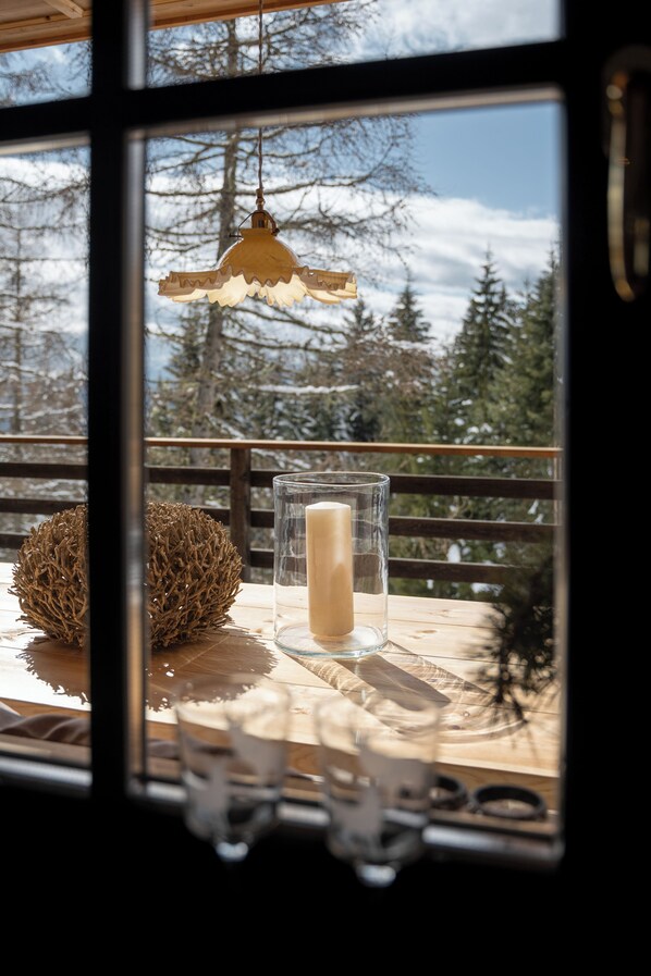 A wooden table with a glass candle holder and a candle, a decorative sphere, and a hanging lamp. - Ihre Auszeit IM Mountain Chalet Avidea Secret IN Hafling (Hafling)