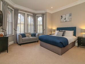 A bedroom with a large bed, a sofa, and a nightstand. - 7 Belgrave Apartments (Ilfracombe)