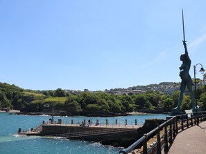 A coastal pier with a statue, a fishing area, and a town in the background. - 7 Belgrave Apartments (Ilfracombe)