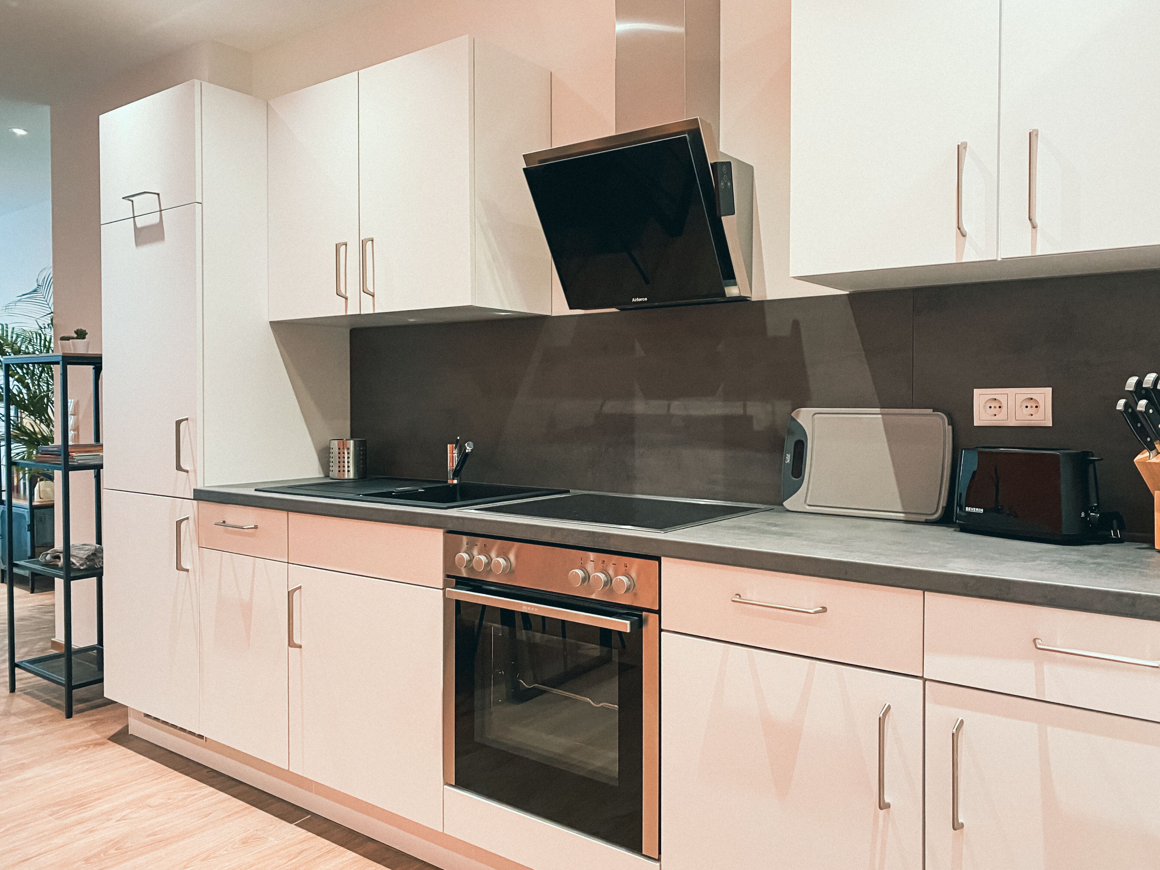 A modern kitchen with white cabinets, a built-in oven, a microwave, and a toaster.