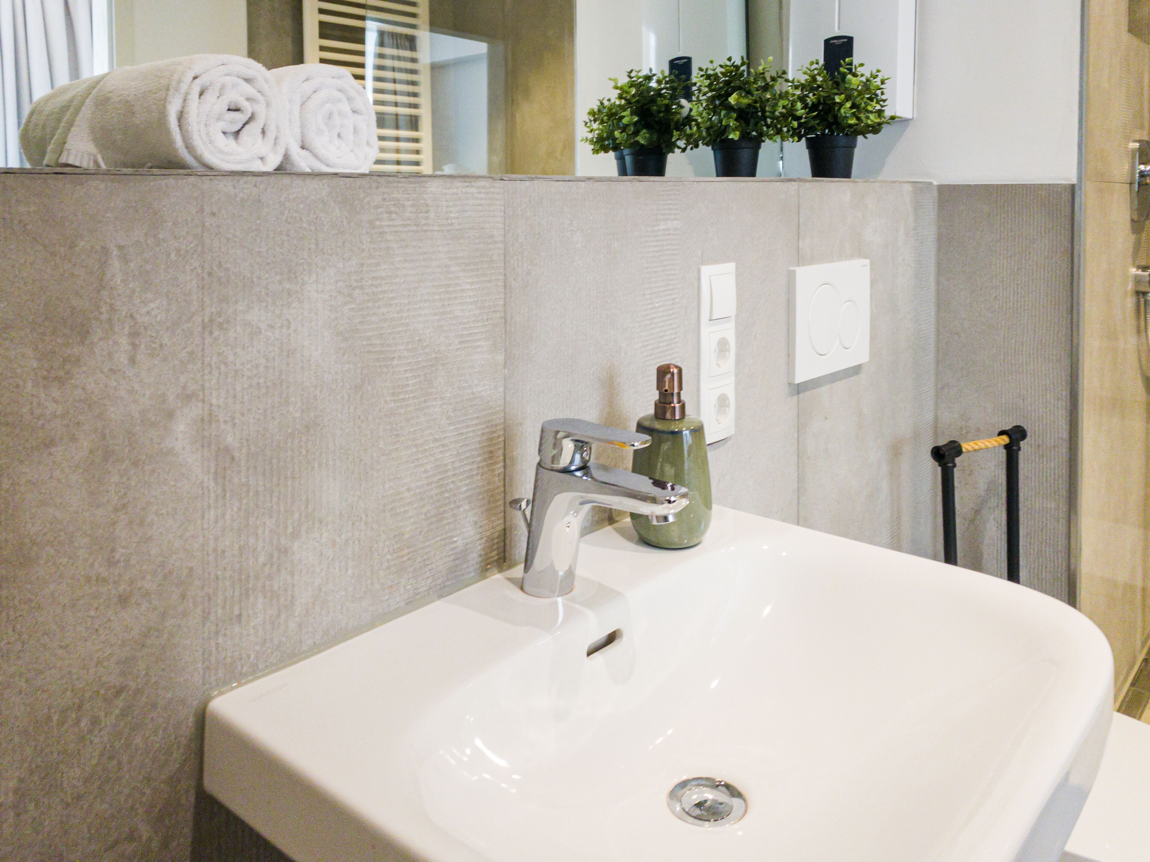 Un bagno con un lavandino bianco, un asciugamano e uno specchio.