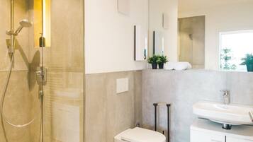 Ein modernes Badezimmer mit Duschkabine, Toilette, Waschbecken und Spiegel.