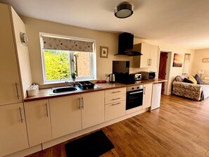 Eine moderne Küche mit Fenster, Spüle, Herd, Mikrowelle und einem Essbereich mit einer Couch.