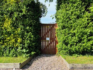 A wooden gate with a sign, surrounded by dense green foliage. - The Old Gate House Annexe (Alford)