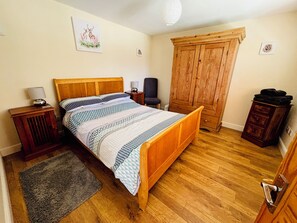 Une chambre à coucher avec un lit en bois, une table de chevet, une commode, une armoire et un tapis.