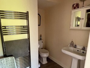 Une salle de bain avec des toilettes, un lavabo et un porte-serviettes.