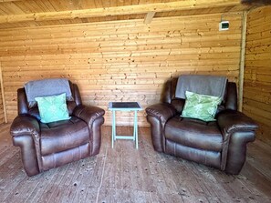 Ein gemütliches Zimmer mit zwei Ledersesseln, einem kleinen Tisch und Holzwänden.