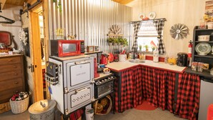 Une cuisine de taille réduite, dotée d’un four vintage, d’un four à micro-ondes et d’un petit évier.