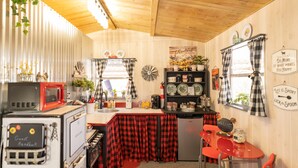 Une cuisine compacte avec une nappe à carreaux rouges et noirs, un four à micro-ondes rouge et un évier de style rétro.