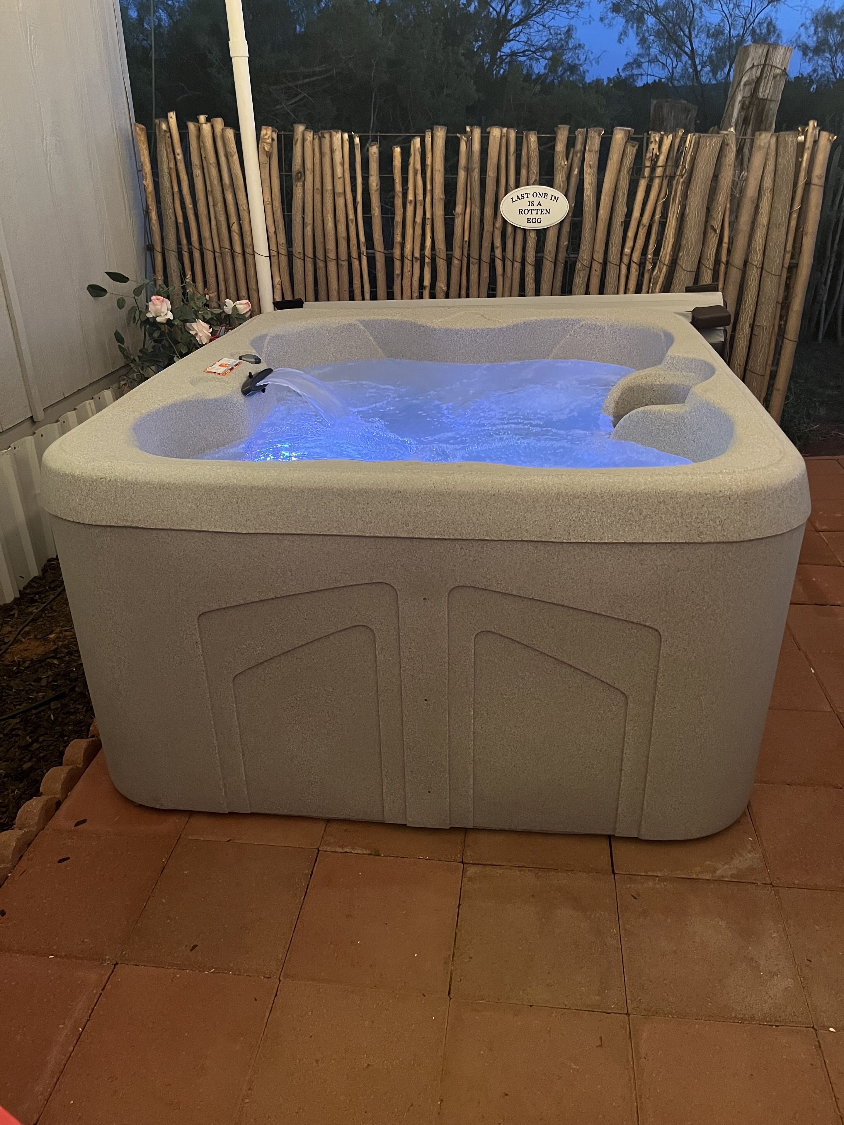 A hot tub with a wooden fence in the background.