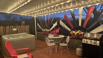 An outdoor patio with a hot tub, seating area, and barbecue grill.