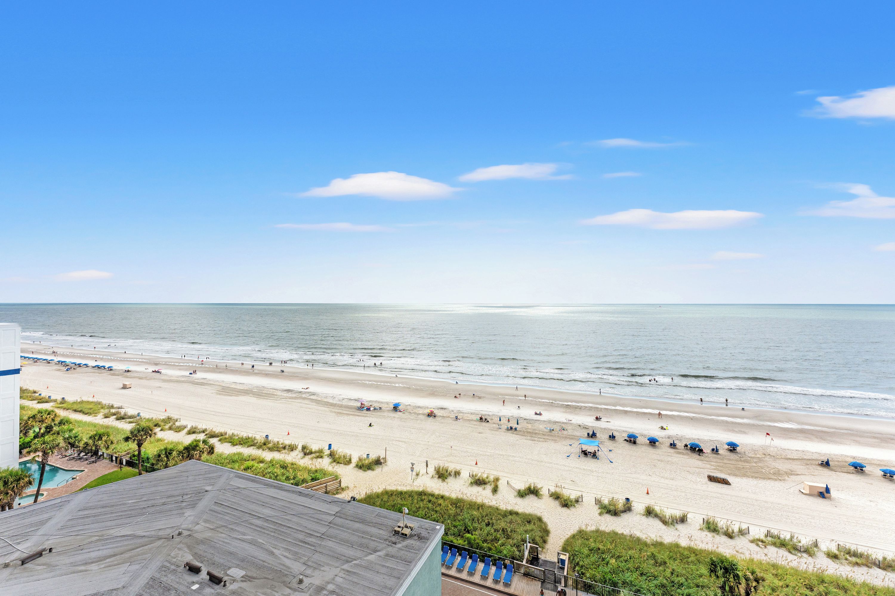 Une vue sur la plage depuis un hôtel doté d’une piscine et de parasols de plage.