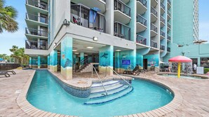 Hotel amb piscina, diversos balcons i un mural tropical.