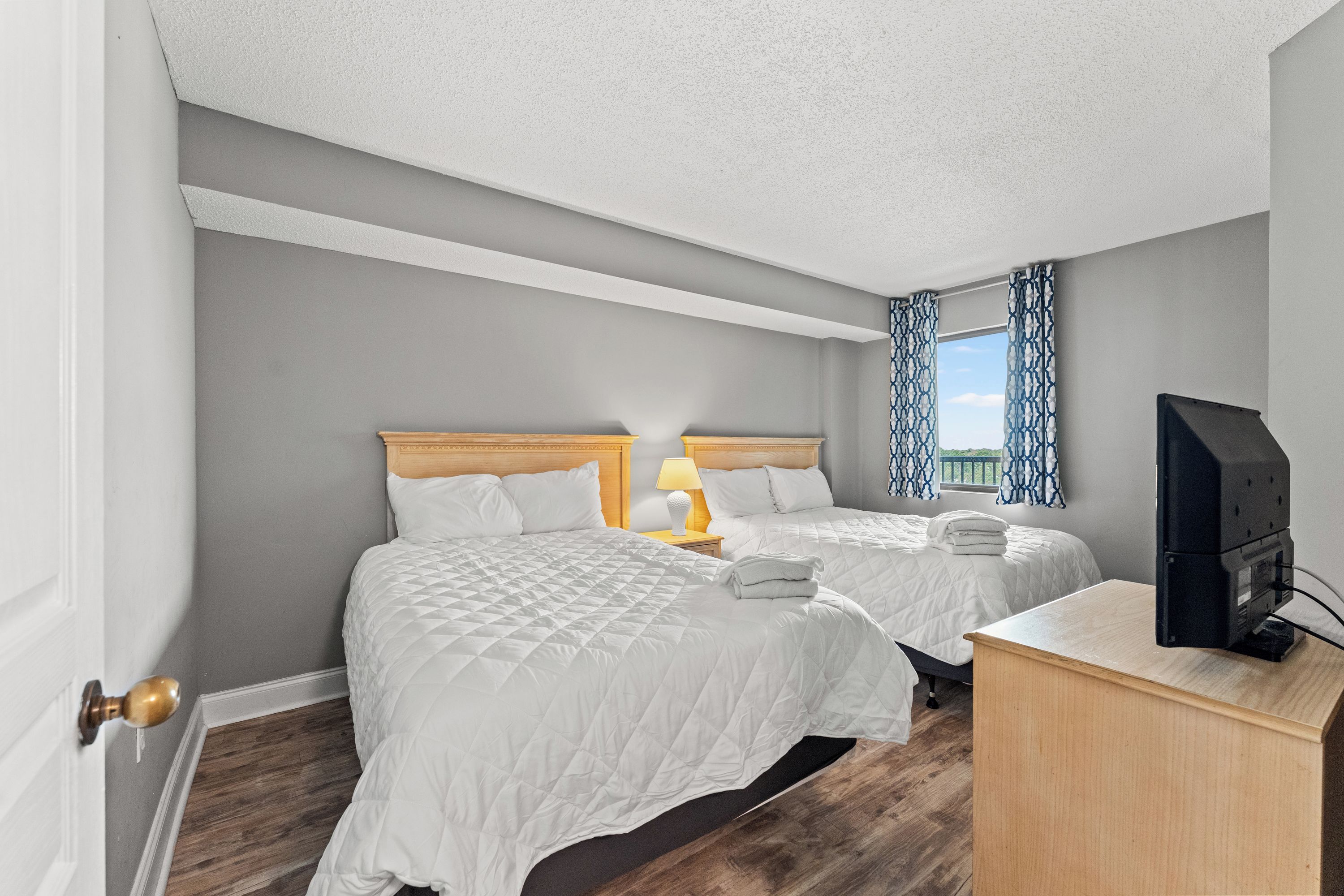 A hotel room with two beds, a desk, and a television.