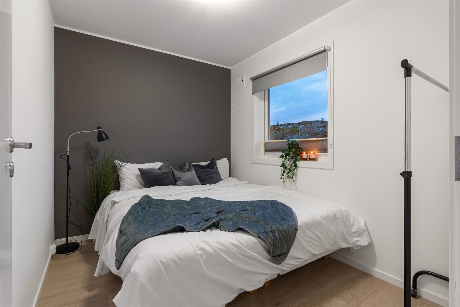 Una camera da letto con un letto, una finestra vista, una lampada da terra e un comodino.
