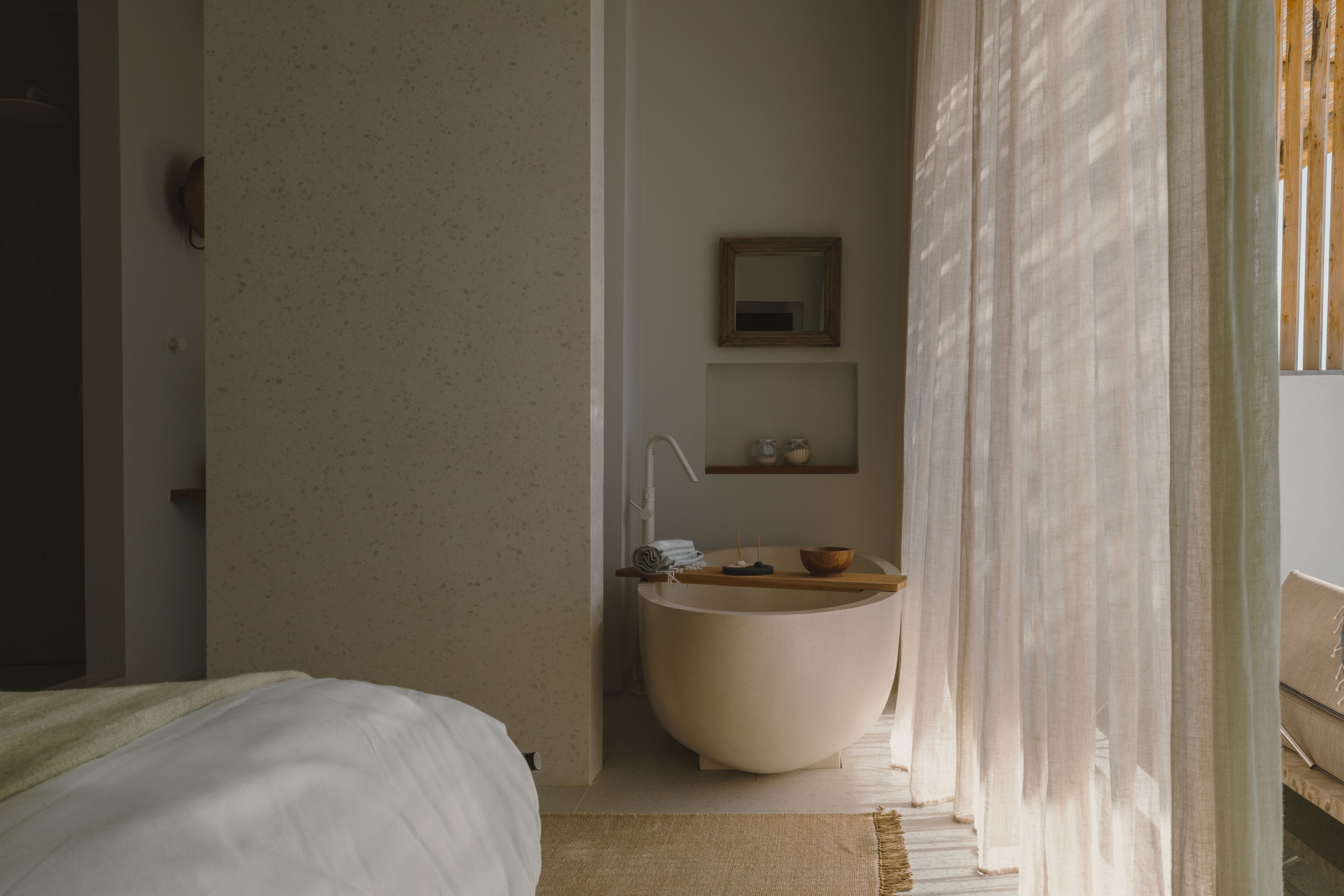 A modern bathroom with a freestanding bathtub, a small shelf with toiletries, and a mirror on the wall.