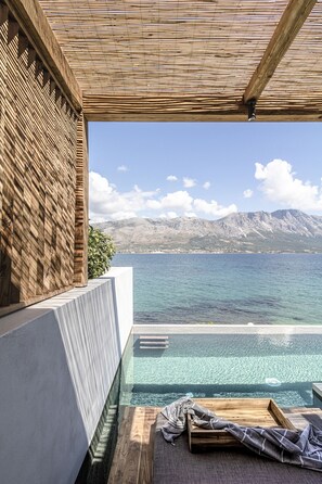 A modern infinity pool with a clear view of the sea and mountains.