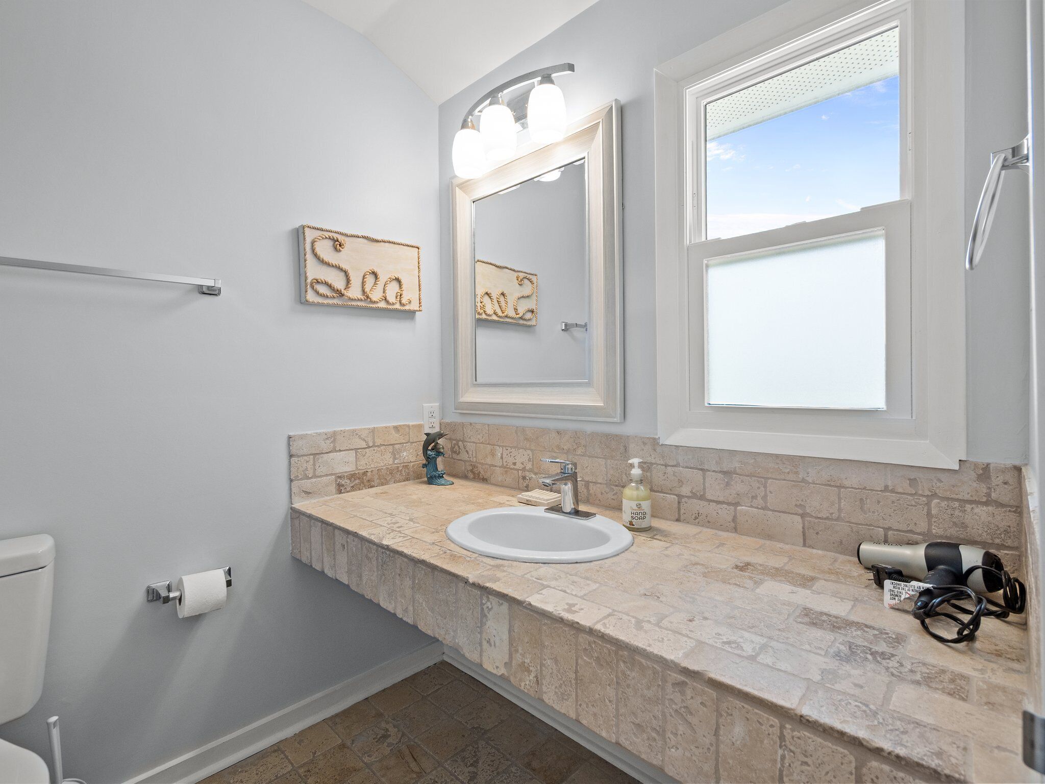 Een badkamer met toilet, wastafel en een grote spiegel.