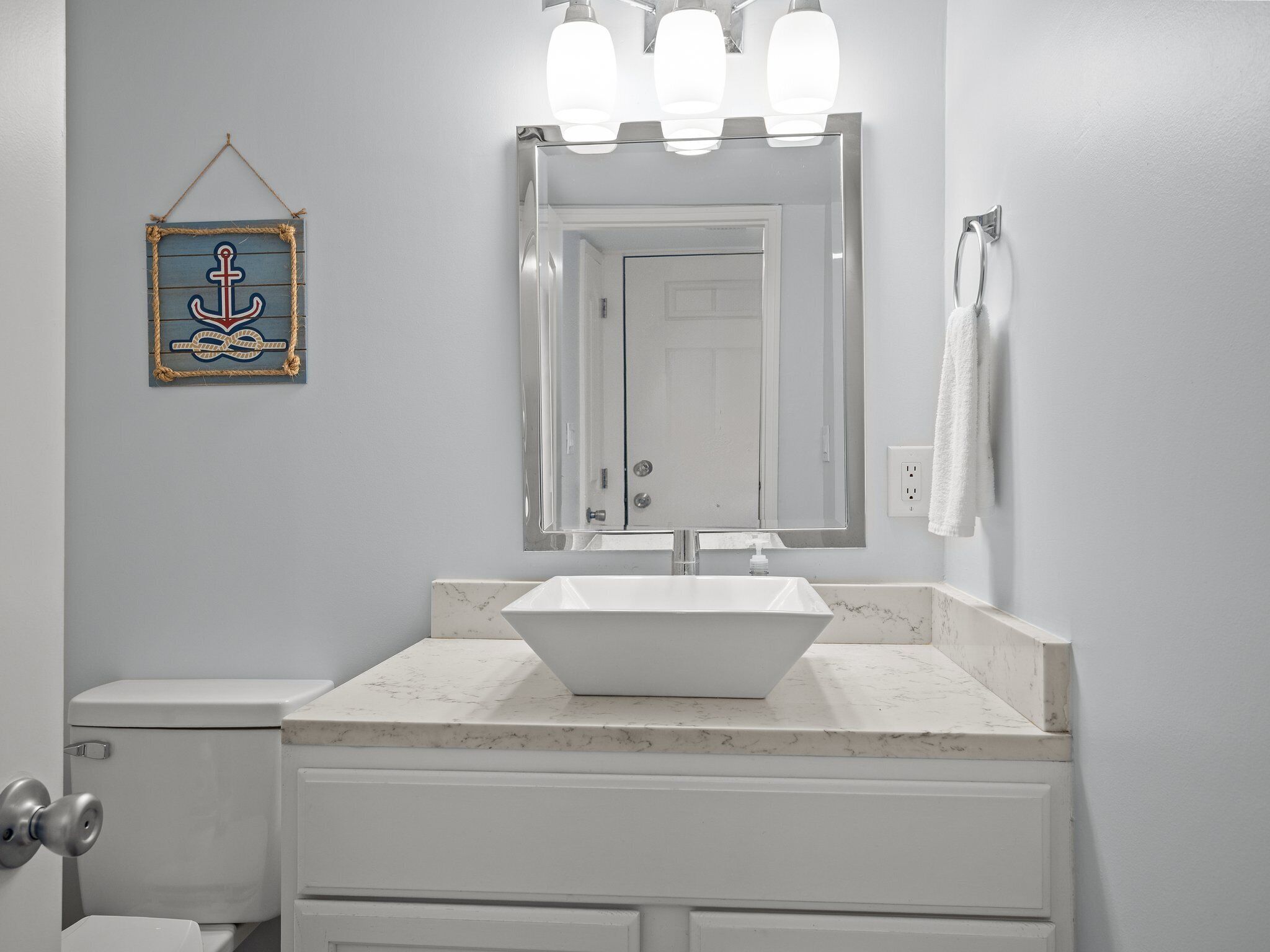 A bathroom with a white sink, a large mirror, and a towel rack.