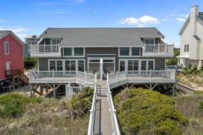 A two-story house with a balcony, a covered entryway, and a wooden deck.